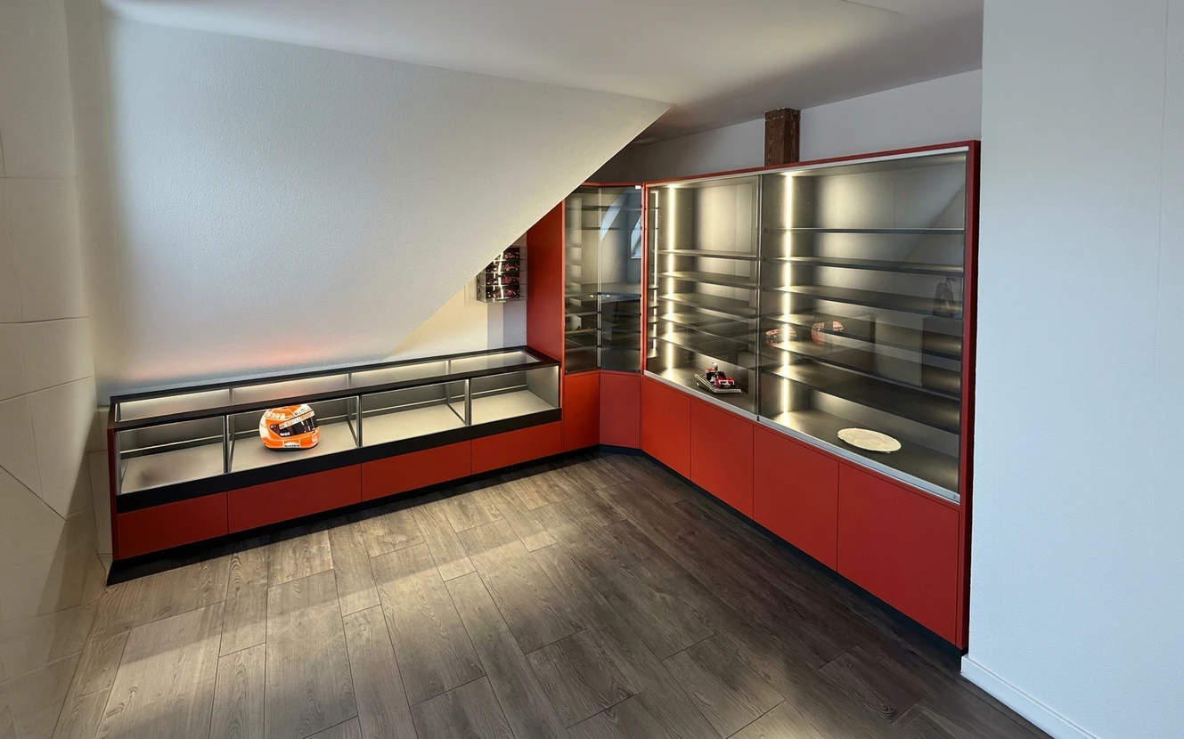 Salle d'exposition sous combles avec mobilier sur mesure en L, laqué rouge ferrari